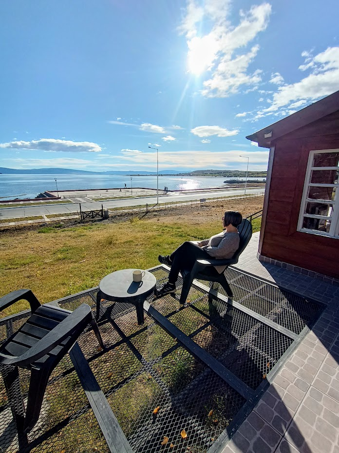 Muestra los sillones que incluye la cabaña y lo lindo que es tomar un cafe mirando al Lago Argentino
